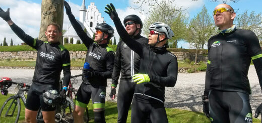 Cykkelryttere nyder søndagssolen med Ullerslev Kirke i baggrunden.